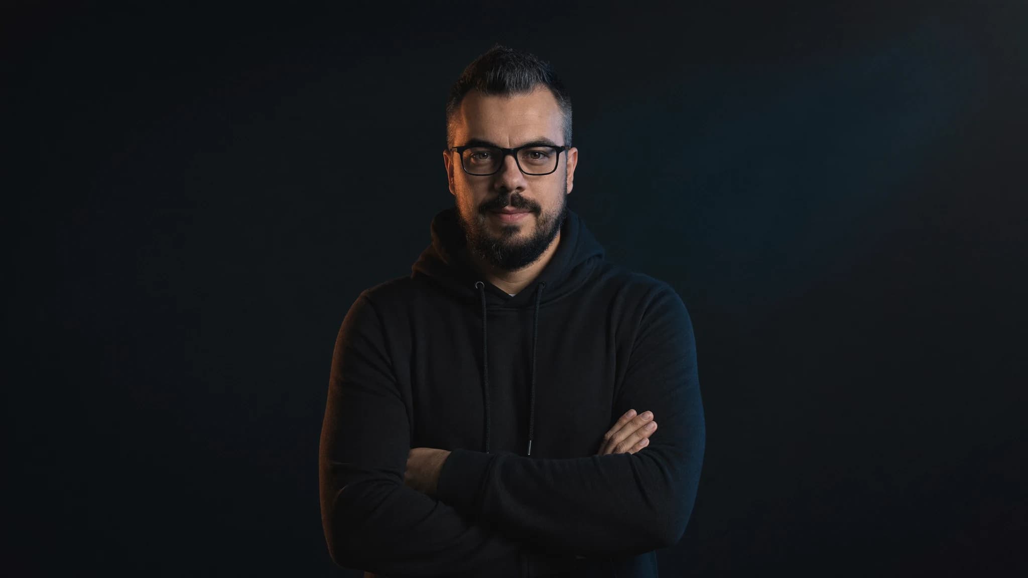 Sönke Berger — Webentwickler für Onlineshops aus Uelzen, Studio-Portrait mit selbstbewusster Pose und verschränkten Armen